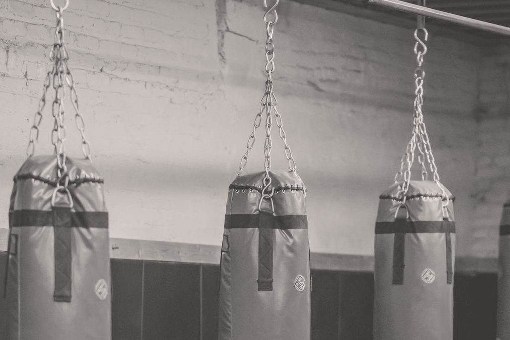 A row of heavy bags hanging on chains along a gym wall