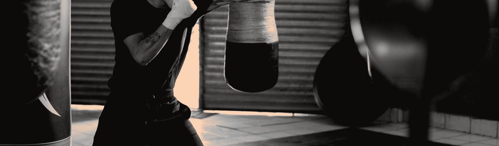A boxer working the heavy bag in a gym, seen from behind