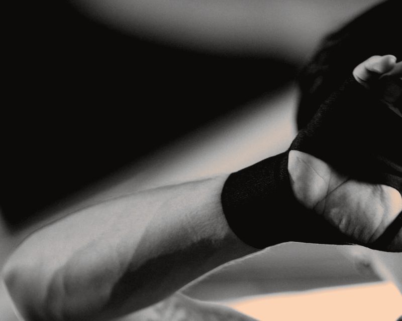 Close-up of a hand and forearm being wrapped in a black cloth hand wrap
