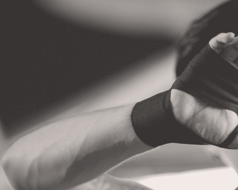 Close-up of a hand and forearm being wrapped in a black cloth hand wrap