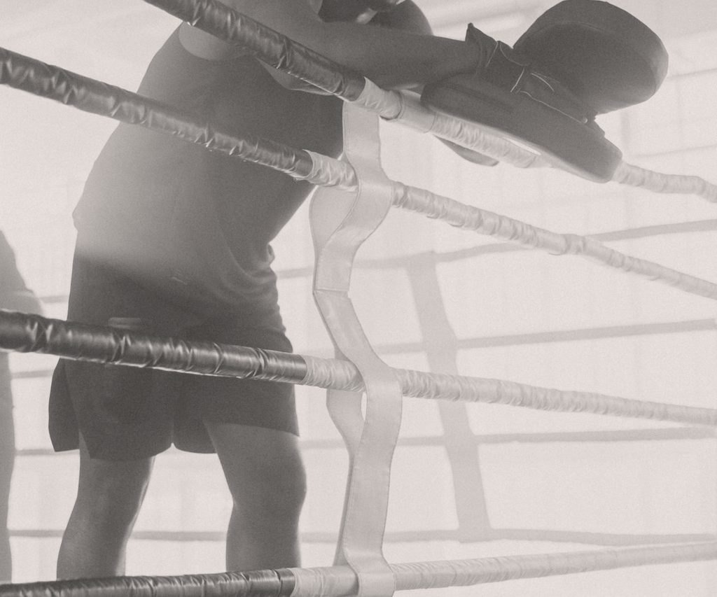 A boxer resting on the ropes of a training ring