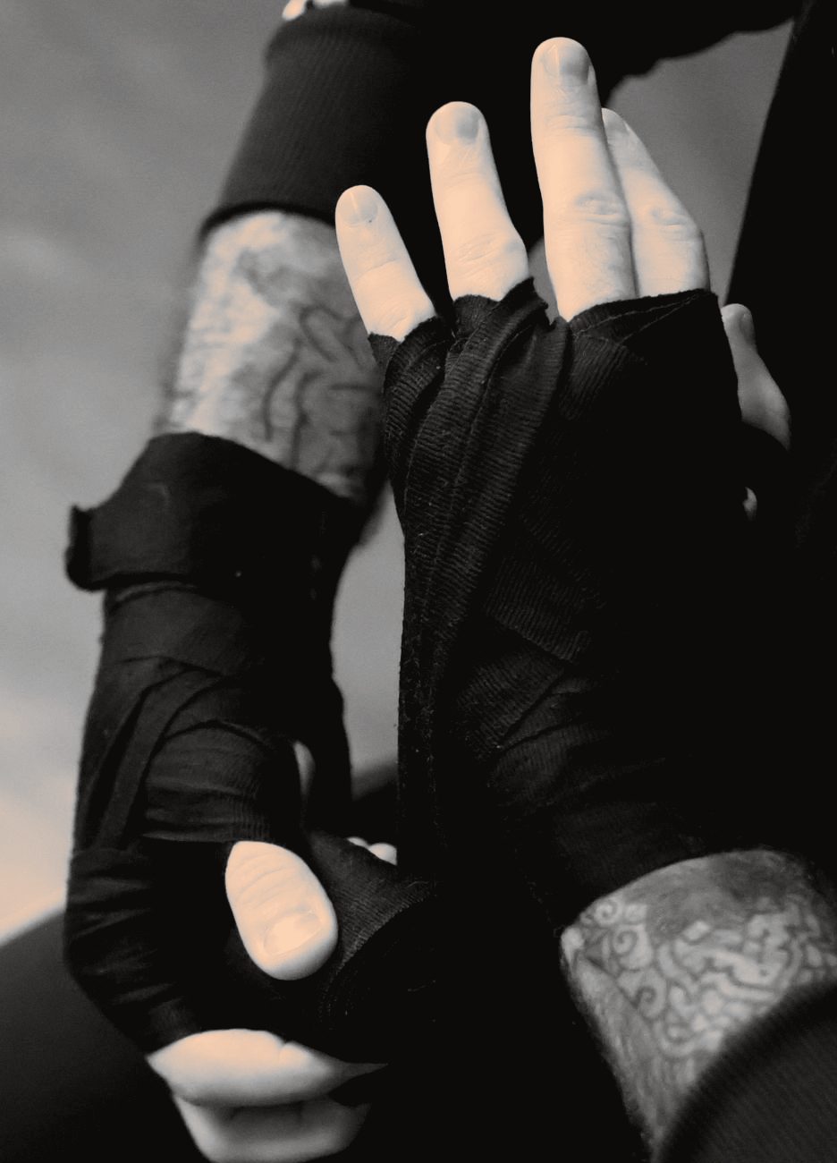 Two hands already taped in black boxing wraps, raised to guard